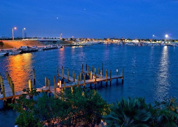 Stunning waterfront marina with a dock extending into the water, surrounded by lush greenery and a bridge in the background.