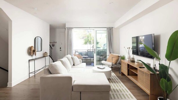 Un salon moderne avec un canapé blanc, une table basse et un téléviseur posé sur un meuble en bois.