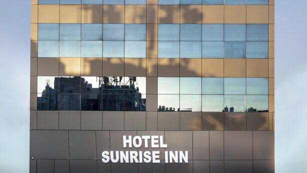 A modern building with a glass facade and the text "HOTEL SUNRISE INN" at the bottom. - Hotel Sunrise Inn (Noida)