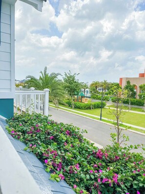 A residential area with a white fence, a street, and a building with a green roof. - Novaworld Phan Thiet - QT Villa (Tien Thanh)