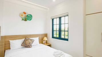A hotel room with a bed, a window, a wardrobe, and a wall clock.
