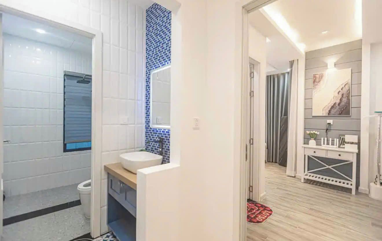 Une salle de bain moderne avec un lavabo blanc, une douche carrelée de bleu et un meuble-lavabo en bois.