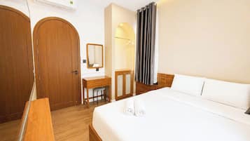 A hotel room with a bed, a desk, a chair, a wardrobe, and a mirror.