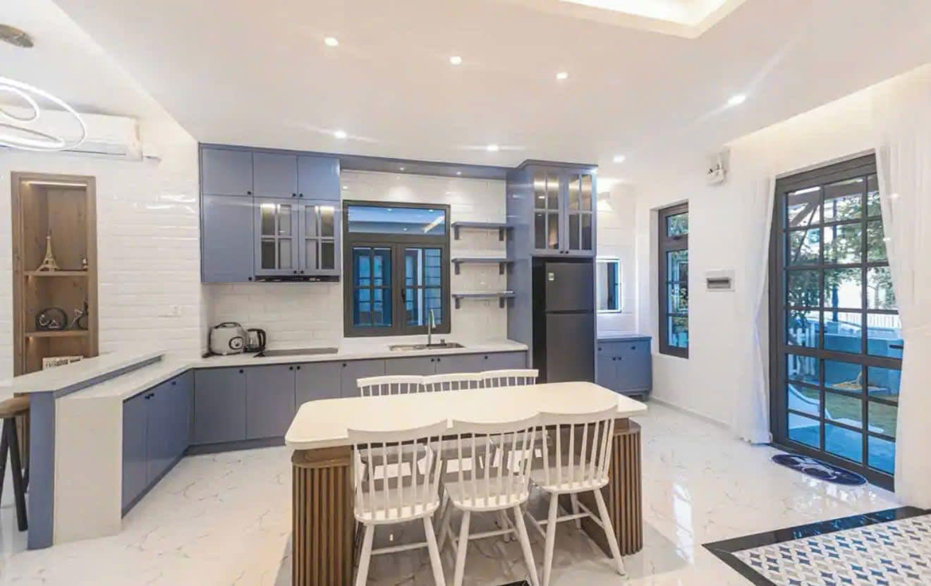 A modern kitchen with a central island, built-in cabinets, and a large window.