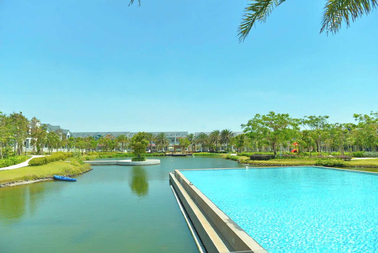 Ein großer Schwimmteich mit klarem, blauem Wasser, umgeben von viel Grün und einer ruhigen Wasseroberfläche.