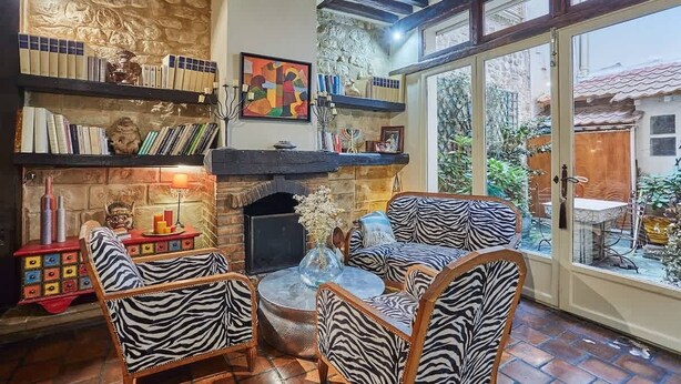 A cozy living room with a fireplace, bookshelves, and zebra-patterned chairs. - Superbe Apartment Le Marais/Place des Vosges (Paris)