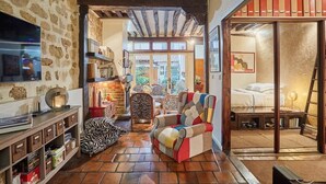 A cozy living room with a fireplace, a bookshelf, and a colorful armchair. - Superbe Apartment Le Marais/Place des Vosges (Paris)