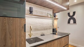 A modern kitchen with a built-in stove, a sink with a gold faucet, and wooden cabinetry.
