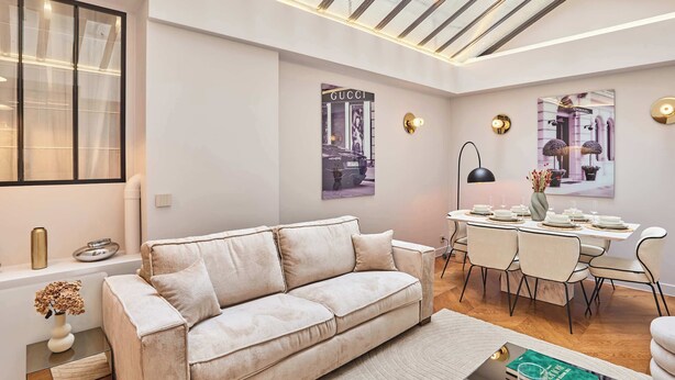 A modern living room with a sofa, a dining table set for six, and a large window with a view of the city.