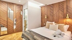 A modern bedroom with a large bed, wooden wardrobe, and a mirror.