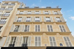 Ein mehrstöckiges Gebäude mit weißen Fensterläden und Balkonen.