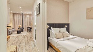 A modern hotel room with a large bed, a desk, a sofa, and a dining area. - Superb Apartment Invalides St Germain des Près (Paris)