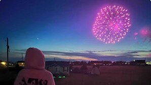 A person standing on a balcony overlooking a fireworks display. - Darnley Dream vacation home perfect to experience PEI to its fullest. (Kensington)