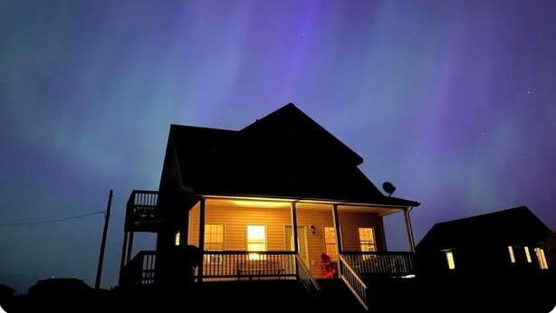 A house with a porch and a person sitting on the steps. - Darnley Dream vacation home perfect to experience PEI to its fullest. (Kensington)