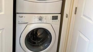 A stacked washer and dryer unit in a hallway. - Darnley Dream vacation home perfect to experience PEI to its fullest. (Kensington)
