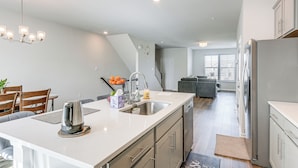 A modern kitchen with a central island, stainless steel appliances, and a dining area with wooden chairs. - 2 Mi to Dtwn Frederick: Updated Townhome (Frederick)