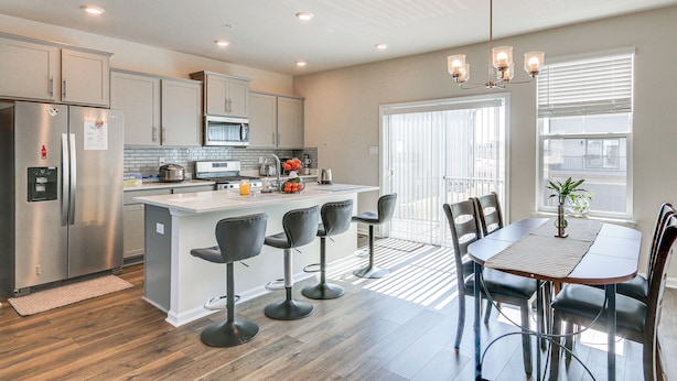 A modern kitchen with a central island, bar stools, and a dining table with chairs. - 2 Mi to Dtwn Frederick: Updated Townhome (Frederick)