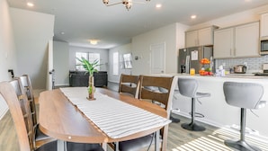 A modern kitchen with a wooden dining table, bar stools, and a chandelier. - 2 Mi to Dtwn Frederick: Updated Townhome (Frederick)