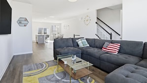 A modern living room with a sectional sofa, a glass coffee table, and a staircase. - 2 Mi to Dtwn Frederick: Updated Townhome (Frederick)