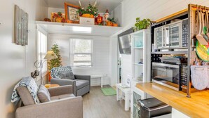 A compact living space with a kitchenette, a sofa, a dining table, and a small green rug.