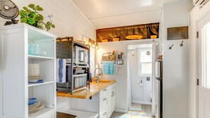 A compact kitchen with white cabinetry, a wooden countertop, and a small dining area.