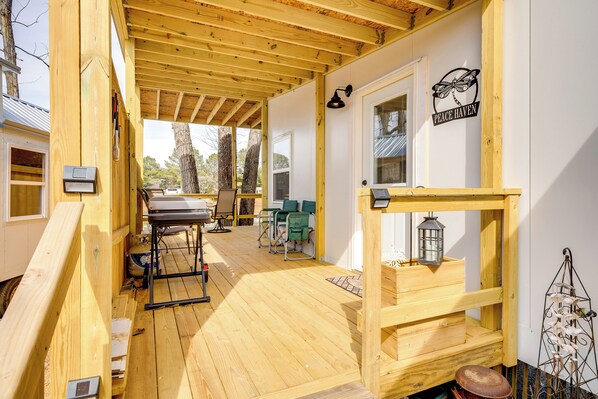 A covered wooden deck with a table and chairs, a wheelchair, and a sign reading "Peace Haven".