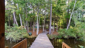 A wooden boardwalk leading through a forested area with a water body on either side. - Water You Wating For? | Waterfront Fun & Relaxation (Boydton)