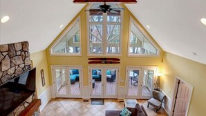 A spacious loft with a high ceiling, large windows, and a stone fireplace. - Water You Wating For? | Waterfront Fun & Relaxation (Boydton)