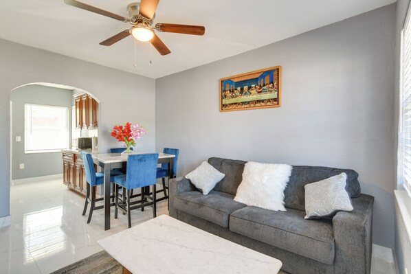 A living room with a gray sofa, white and gray cushions, a coffee table, and a painting of The Last Supper on the wall. - 8 Mi to Dtwn: Apartment in Miami (Miami Shores)
