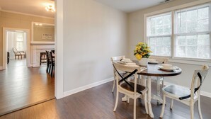 A dining area with a round table, white chairs, and a vase with yellow flowers. - Updated & Charming! Home Near Douthat State Park (Clifton Forge)