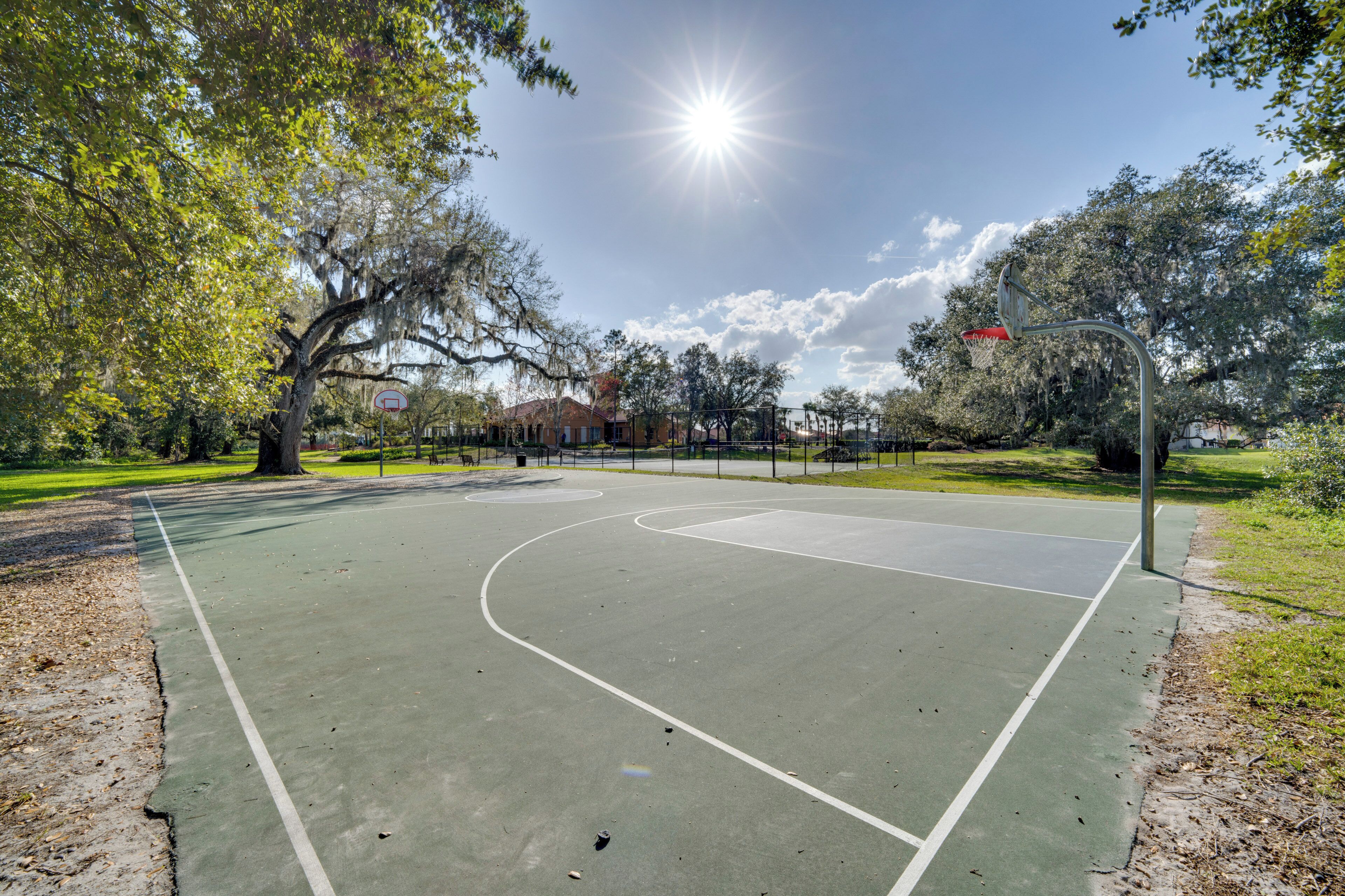 Un terrain de basket en plein air, avec un ciel dégagé et des arbres.