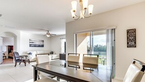 Amplia sala de estar con una gran mesa de comedor, asientos cómodos, un ventilador de techo y vistas a través de una puerta corrediza de vidrio.