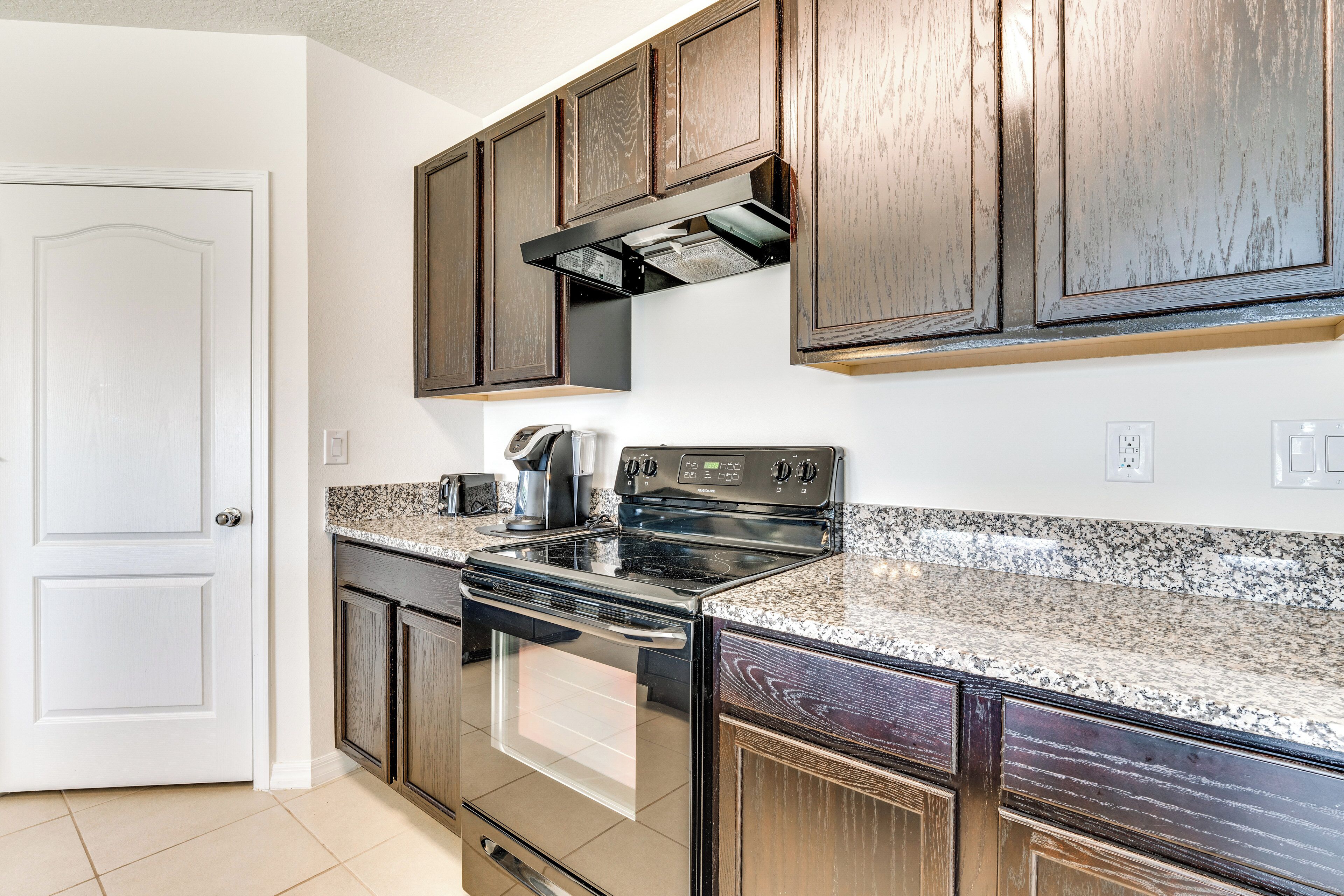 A kitchen with dark wooden cabinets, a stainless steel stove, and granite countertops.