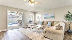 A spacious living room with a beige sofa, a coffee table, and a ceiling fan. - Saltwater Pool & Spa at Home in Bradenton (Bradenton)