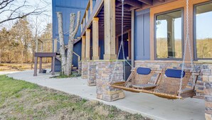A building with a porch, stone pillars, and a swing chair. - Lakefront Gem: Dock & Hot Tub in Jacksboro (Jacksboro)