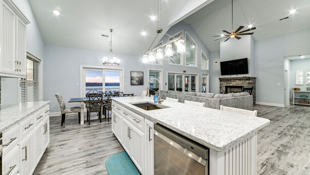 A spacious kitchen with a large island, white cabinetry, and a built-in dishwasher.