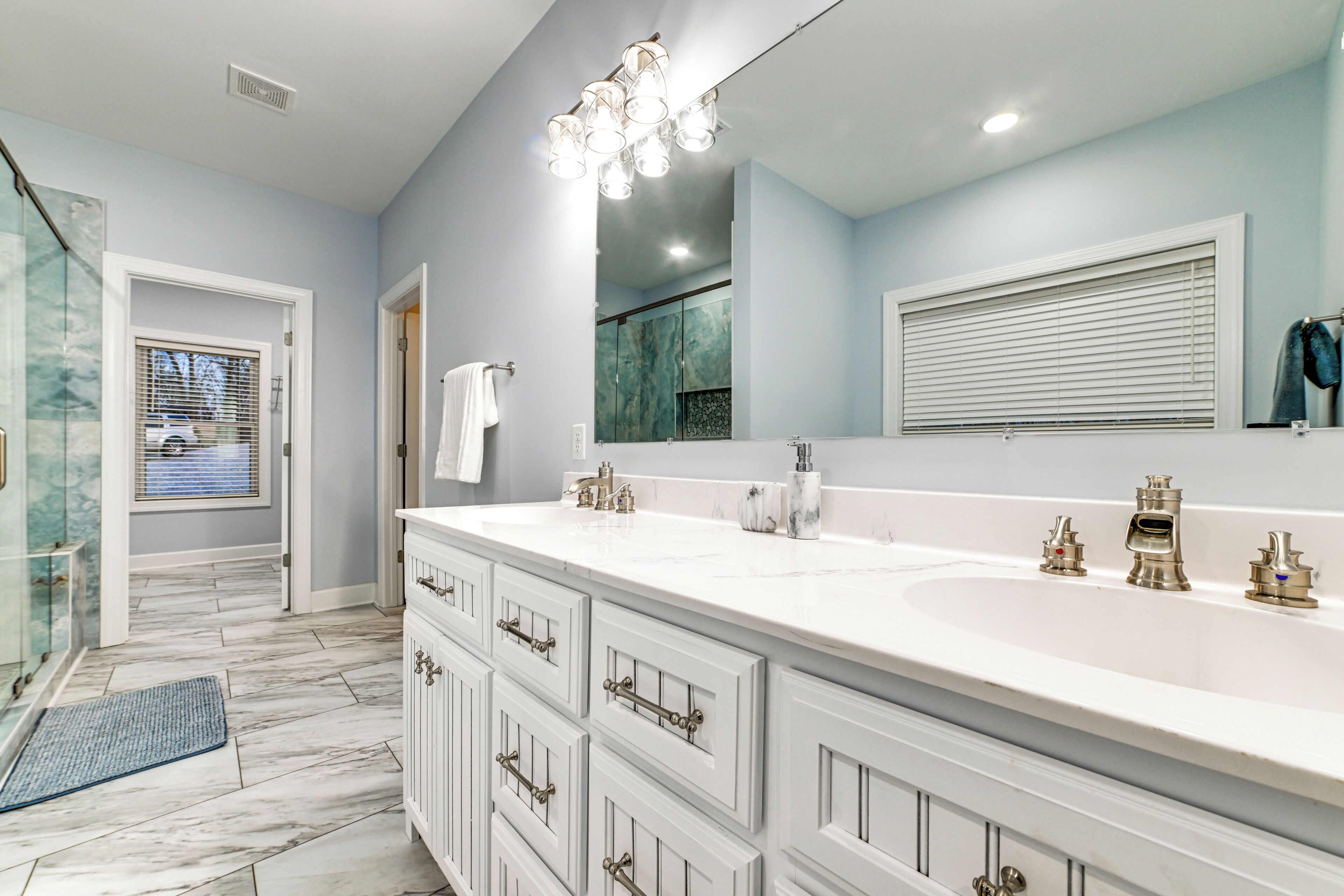 Un bagno moderno con un ampio lavabo bianco, un box doccia in vetro e un grande specchio.