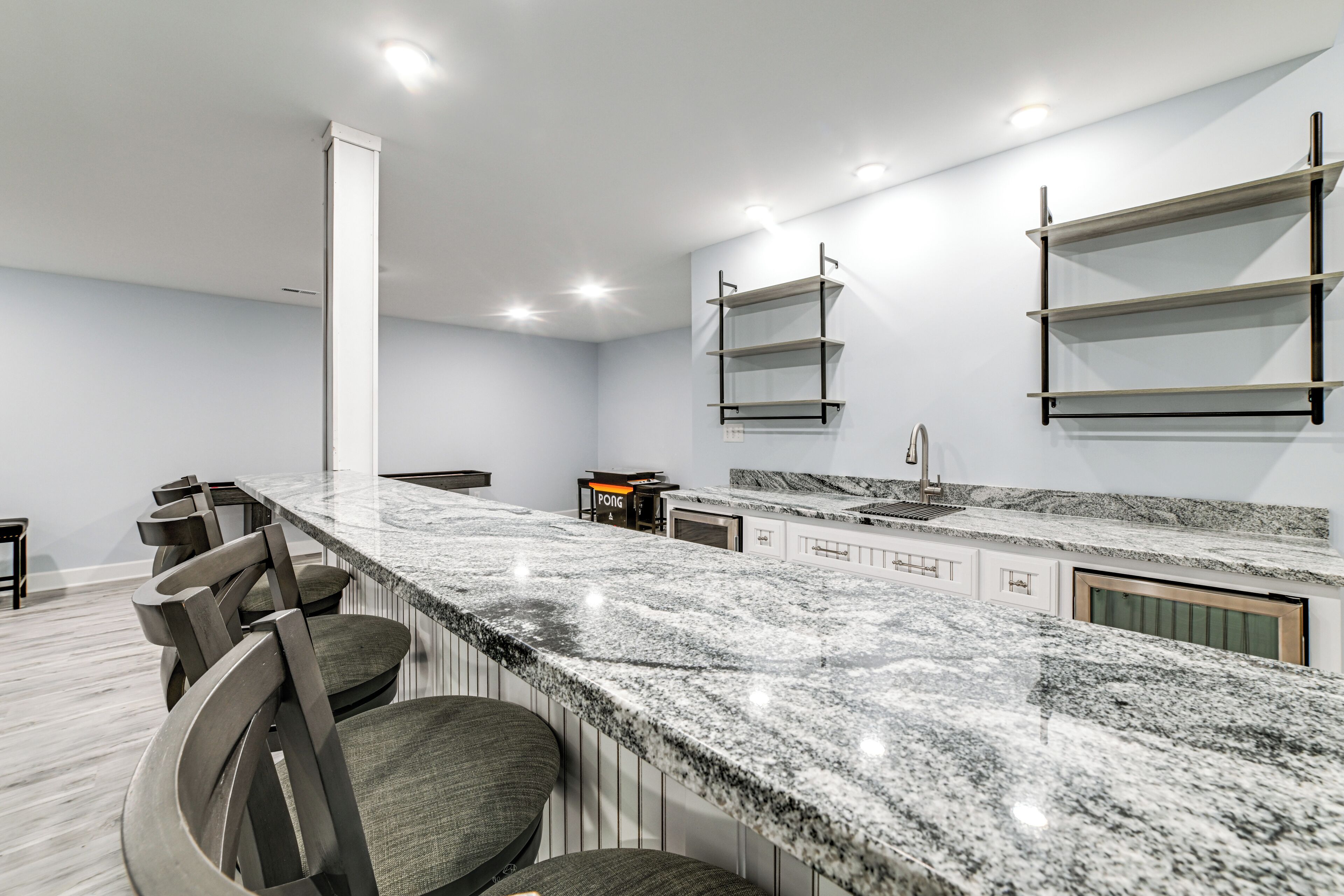 Una cocina moderna con encimera de granito, asientos tipo bar y estanterías integradas.