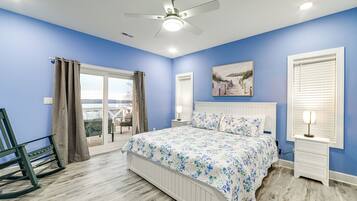 A bedroom with a bed, a nightstand, a chair, a ceiling fan, and a window with curtains.