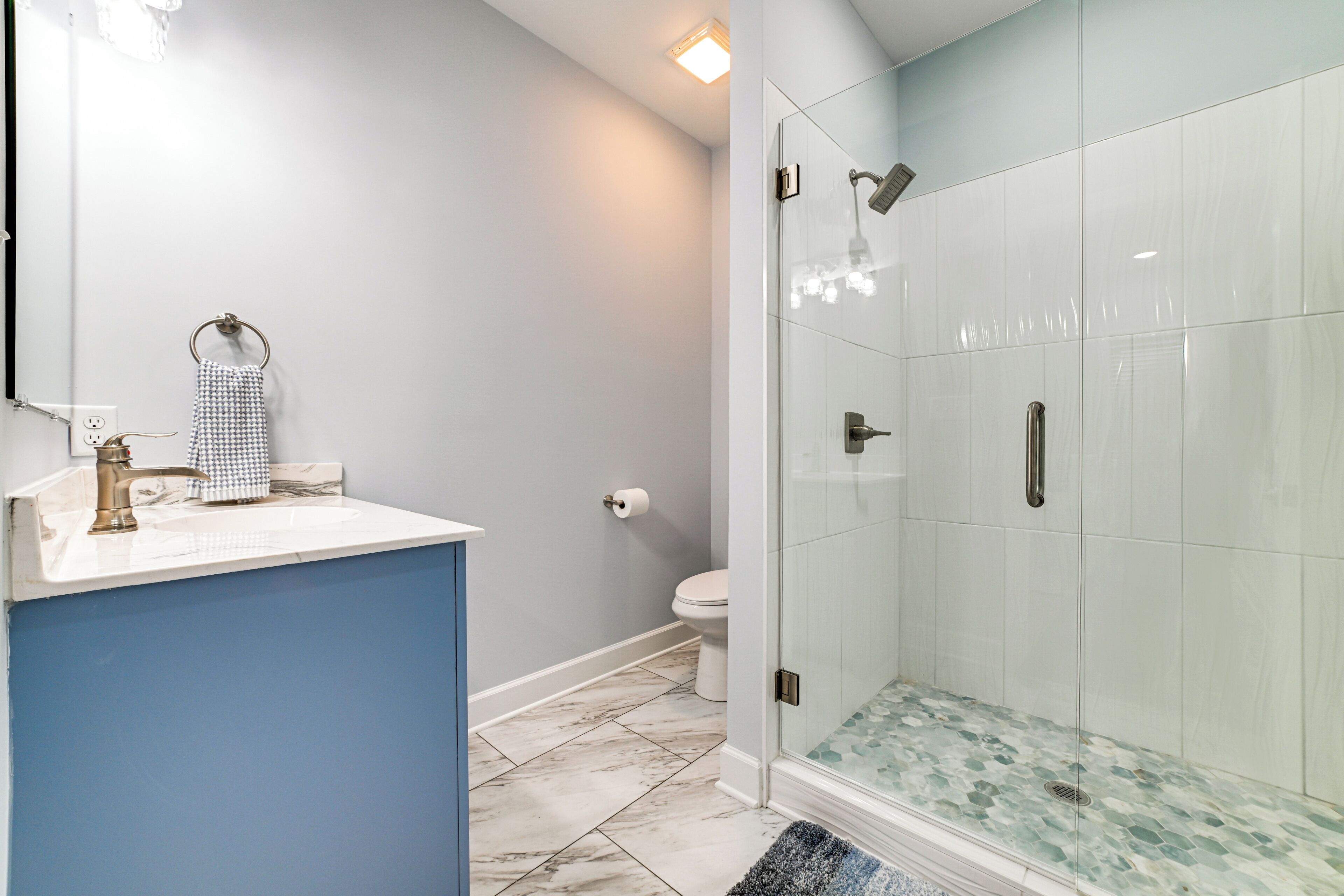 A bathroom with a glass-enclosed shower, a sink with a towel ring, and a toilet.