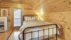 Un dormitorio con paneles de madera, una cama, una lámpara de noche y una puerta a un balcón exterior.