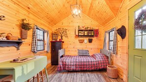 Una habitación de cabaña acogedora, con una cama, una mesa y una silla.