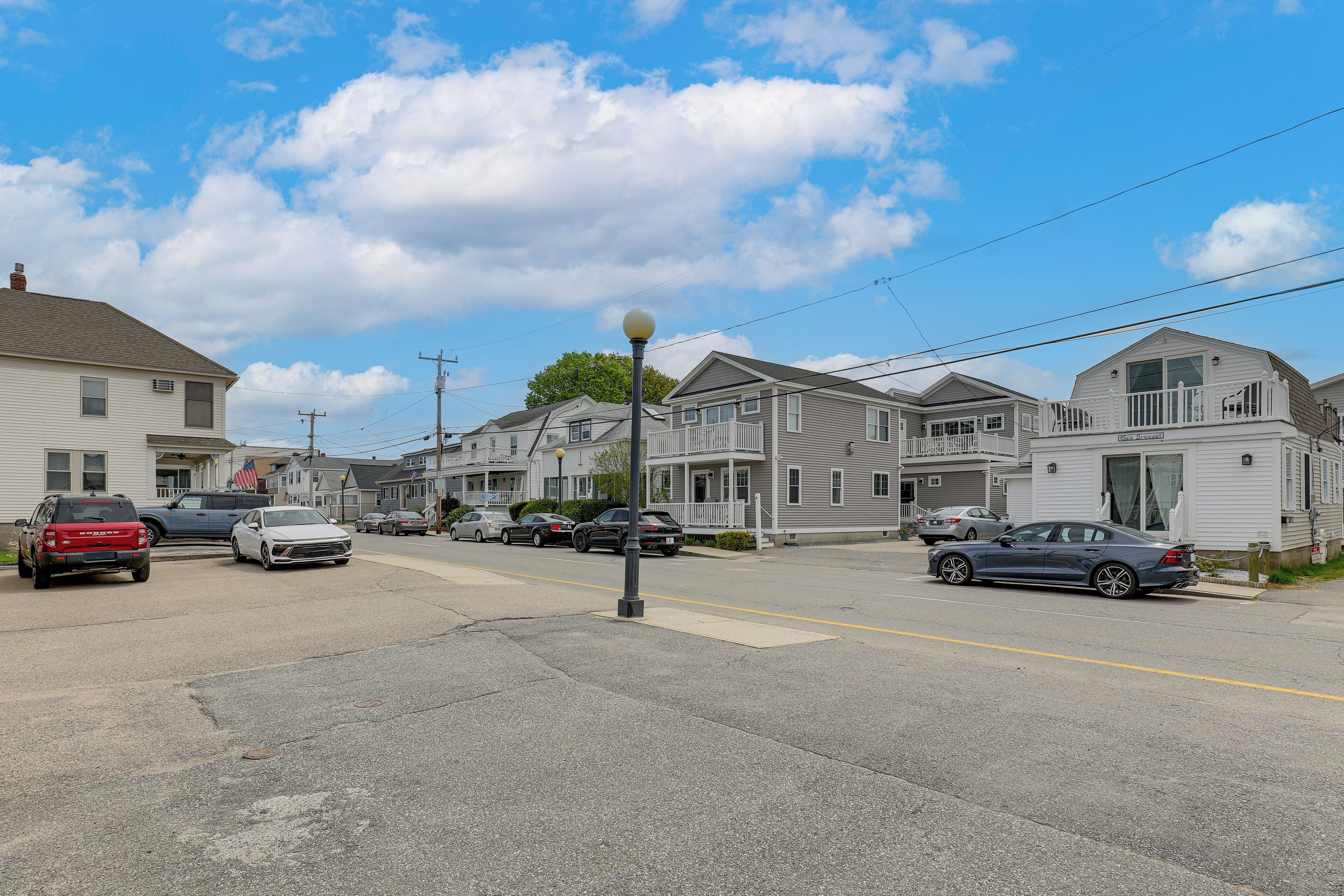 Une rue résidentielle bordée de maisons, avec des voitures garées et un lampadaire.