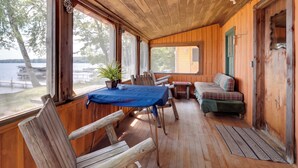A wooden cabin with a dining table, chairs, a sofa, and a view of the lake. - South Twin Lake Cabin w/ Seasonal Dock & Slip! (Conover)