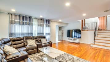 Uma sala de estar moderna com um sofá de couro, uma mesa de centro e uma televisão de tela plana.