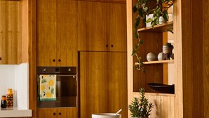 Una cocina moderna con armarios de madera, horno empotrado y encimera blanca.