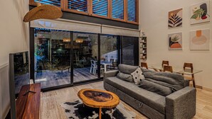 A modern living room with a grey sofa, a wooden coffee table, and a glass sliding door leading to an outdoor area. -  2BR GROUND floor: Pool, Hot tub, Big Gym, Beach Access LUX AWA Playacar (Playa del Carmen)
