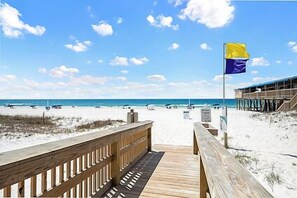Une plage avec une promenade en bois menant à un bâtiment sur lequel flotte un drapeau.