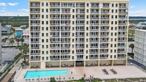 Un hotel de varios pisos con balcones, piscina y vistas del entorno.