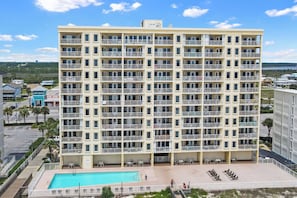 A multi-story hotel with balconies, a swimming pool, and a view of the surrounding area.